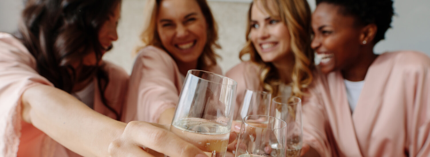 Bridesmaids in pink robes doing a champagne toast