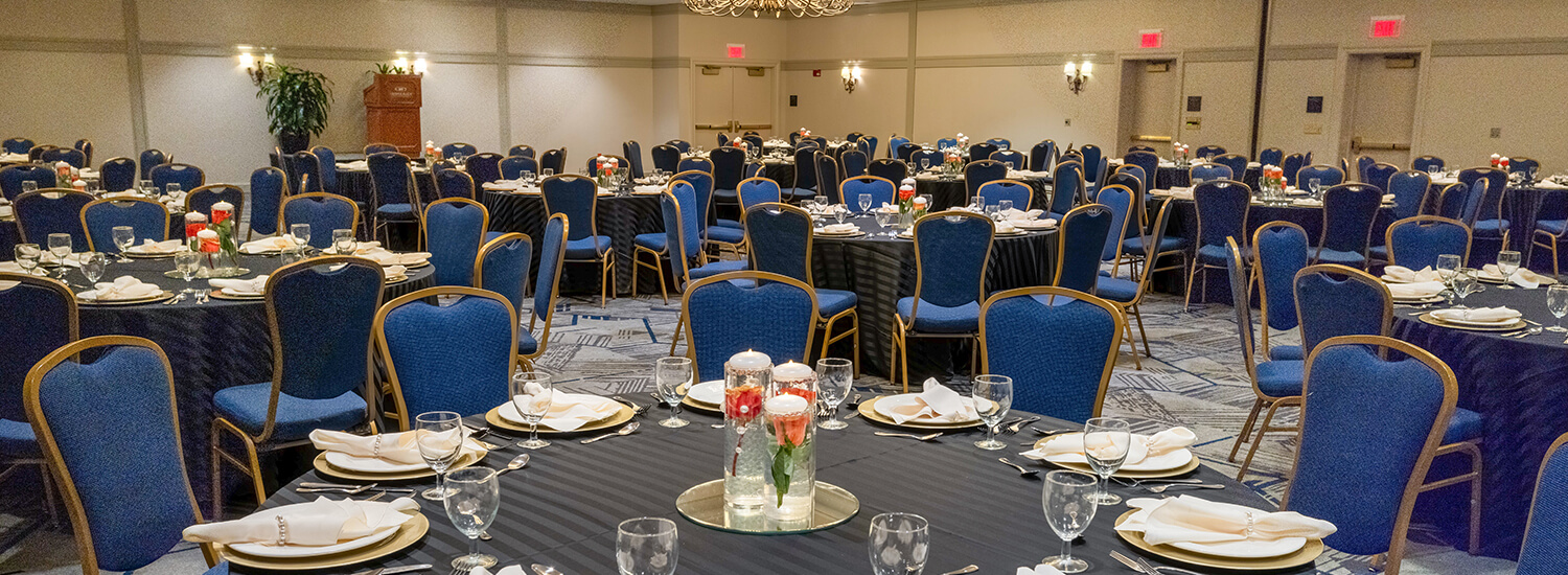 Large ballroom with round, gray tables and blue chairs