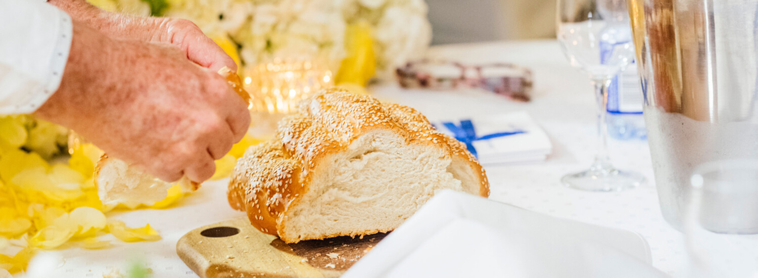 Hands breaking bread on a cutting board