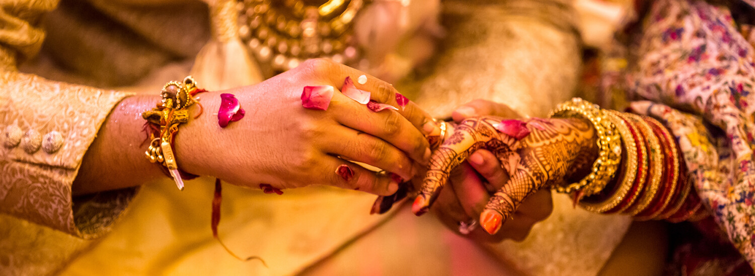 Traditional bride and groom at Indian wedding handing each other rings